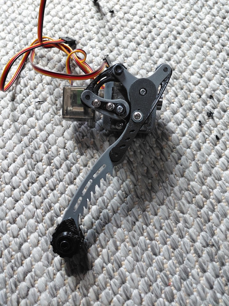 The printed robot leg extended, with a long gray lower leg, black curved links, and a black foot